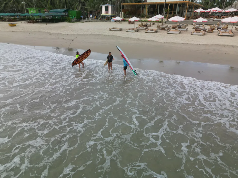 Surfers carrying boards into the water from the beach